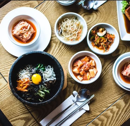 A variety of traditional Korean side dishes (banchan) served in small bowls, symbolizing the communal dining culture and nutritional balance of Hallyu food.
