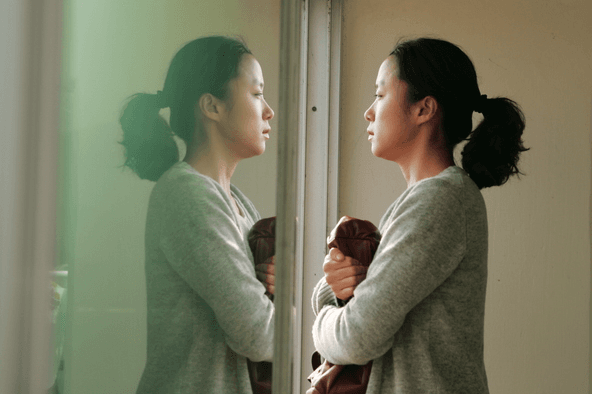 A dramatic still cut from Secret Sunshine (2007) capturing Shin-ae's raw emotional turmoil in a mundane setting, showcasing Lee Chang-dong's realistic cinematography.
